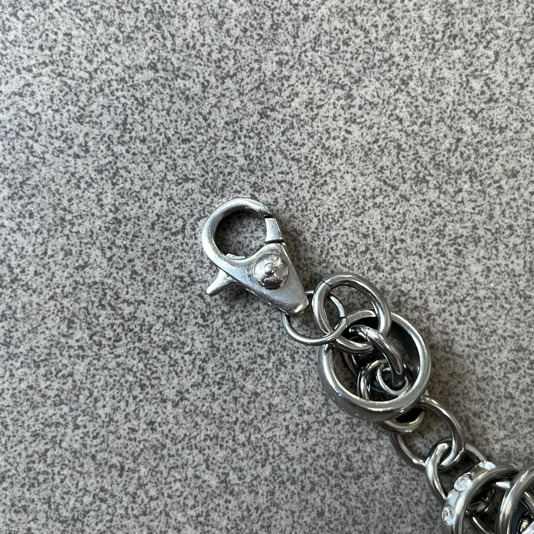 Dolce &amp; Gabbana DJ0777 Crystal Ring Link Bracelet features a stainless steel chain with freely moving rings, including basic loops, D&amp;G-engraved rings and crystal-set rings. The bracelet has a large clasp, while the end is finished with a ball featuring D&amp;G logos all around it.