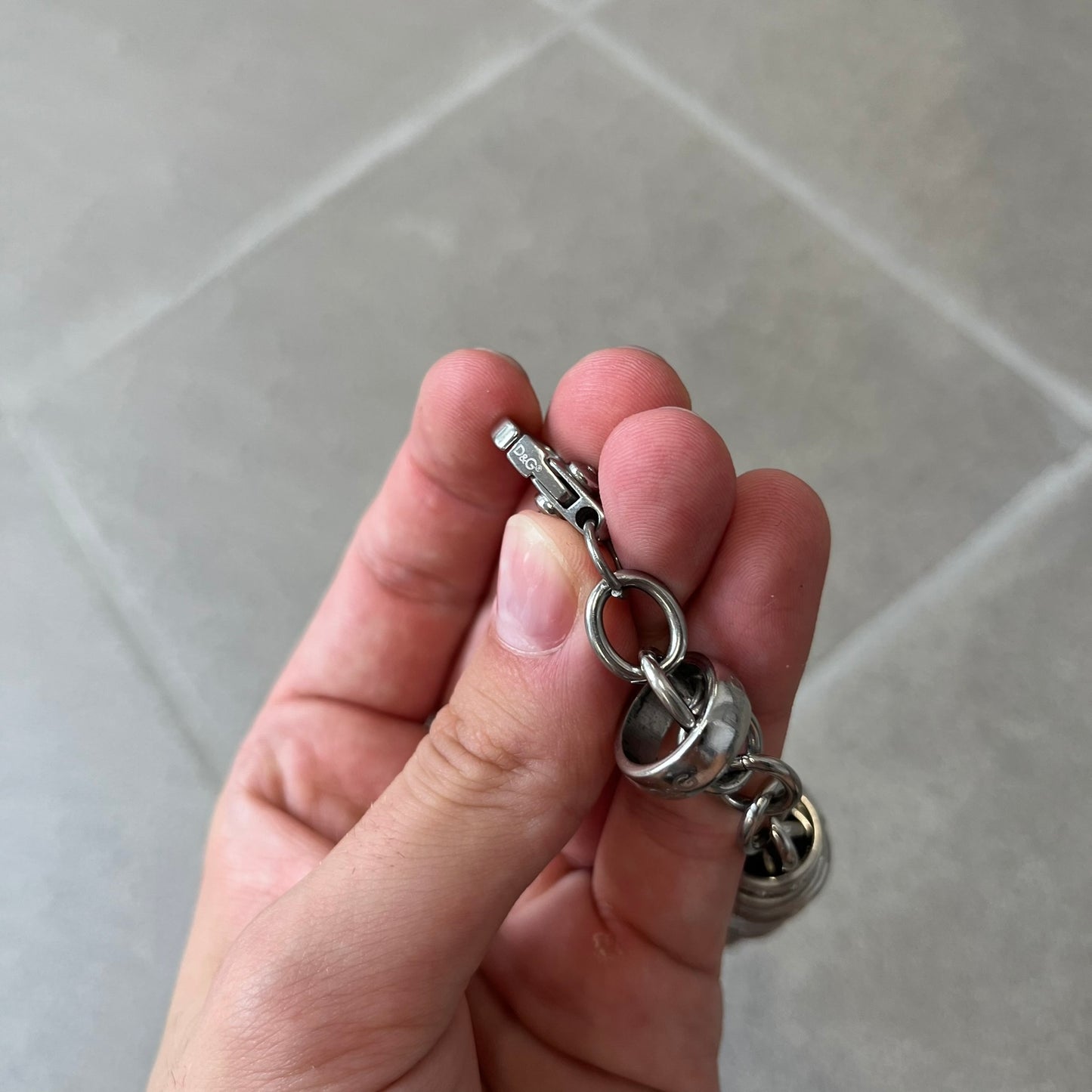 Dolce &amp; Gabbana DJ0777 Crystal Ring Link Bracelet features a stainless steel chain with freely moving rings, including basic loops, D&amp;G-engraved rings and crystal-set rings. The bracelet has a large clasp, while the end is finished with a ball featuring D&amp;G logos all around it.