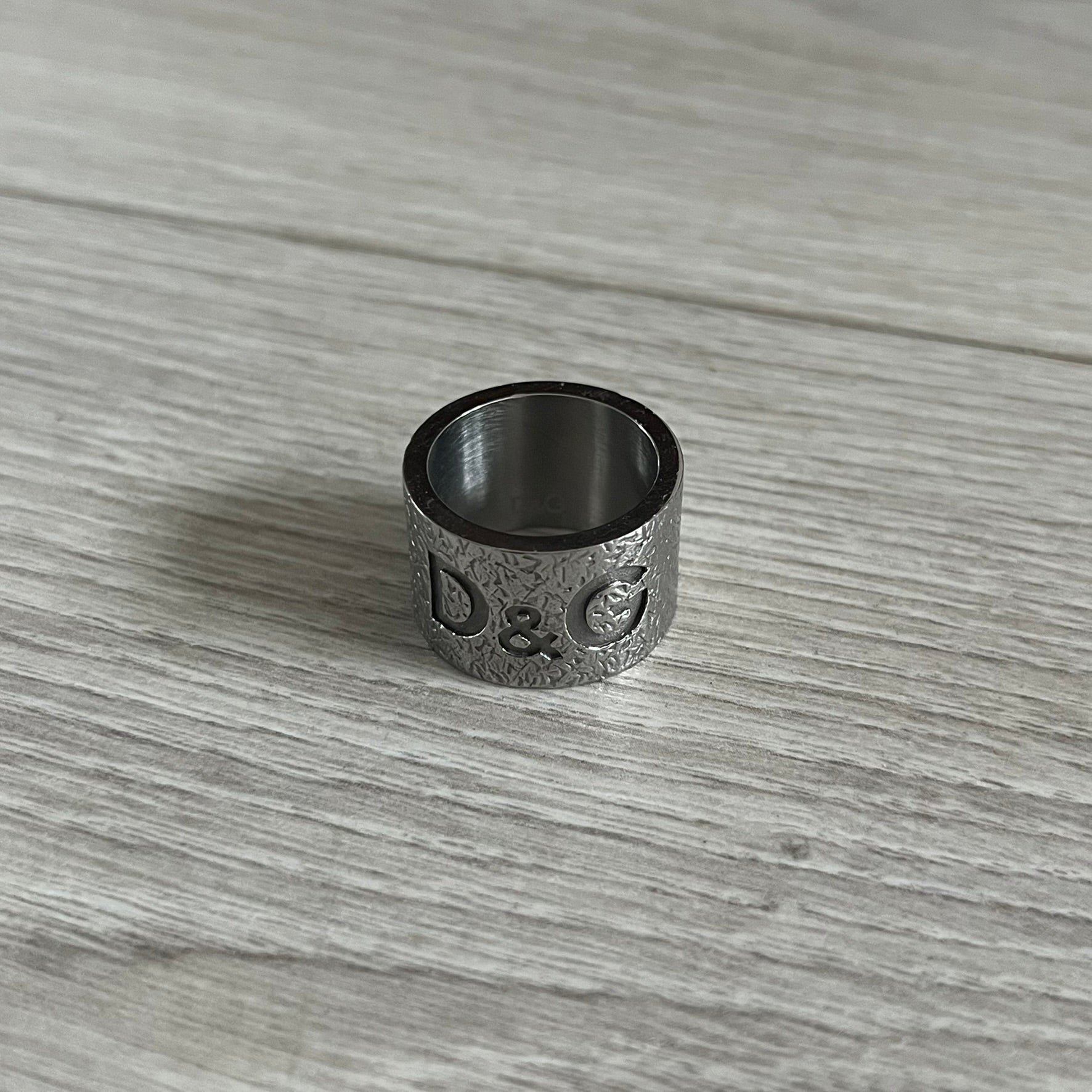 Silver ring with engraved text on a wooden surface