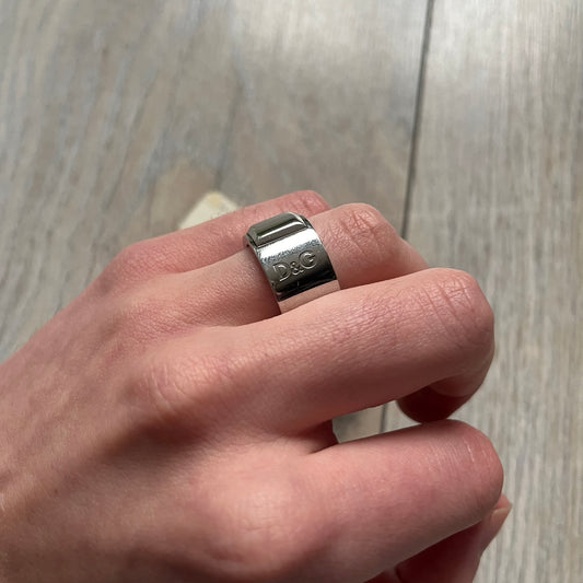 Dolce & Gabbana DJ0836 Ring is made from silver-tone metal and features three raised square elements set across the top. Next to the squares, there is a small engraved D&G logo. The ring has a clean, minimal design and is marked with model code DJ0836.