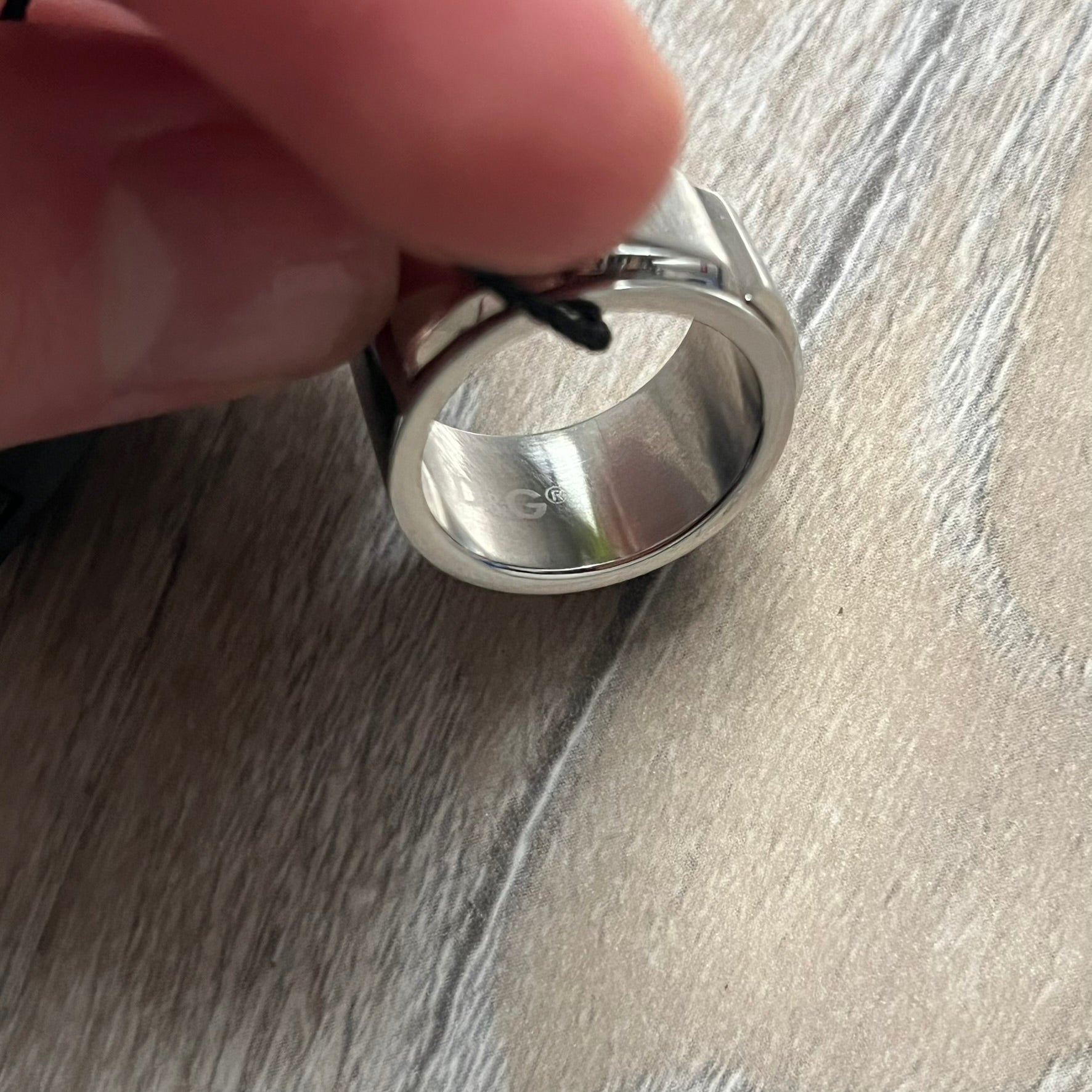 Dolce & Gabbana DJ0836 Ring is made from silver-tone metal and features three raised square elements set across the top. Next to the squares, there is a small engraved D&G logo. The ring has a clean, minimal design and is marked with model code DJ0836.