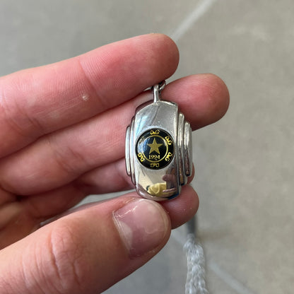 Dolce & Gabbana DJ1067 Gold Star Necklace features a silver-toned rectangular pendant with a black background and a circular plastic center, surrounded by gold D&G logos and a gold star with "1994" text. It comes on a circle-link chain with a large clasp.