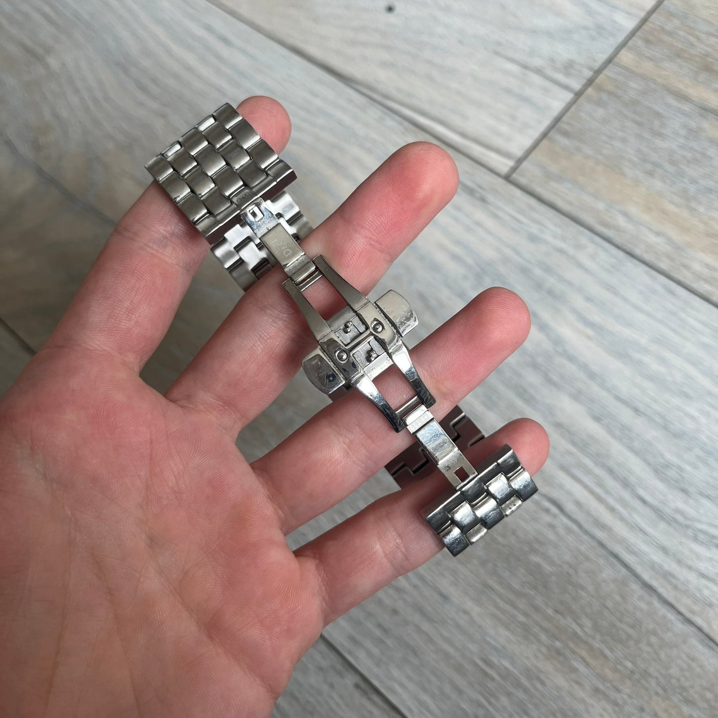 Dolce &amp; Gabbana Rhinestones Analog Watch is a stainless steel quartz watch featuring a square white dial with silver D&amp;G logo and silver hands. The case and bracelet form a continuous design with the face matching the width of the bracelet, and selected areas are set with crystal accents. It includes a dual side-clasp closure, is water resistant to 3 ATM, with removable links.