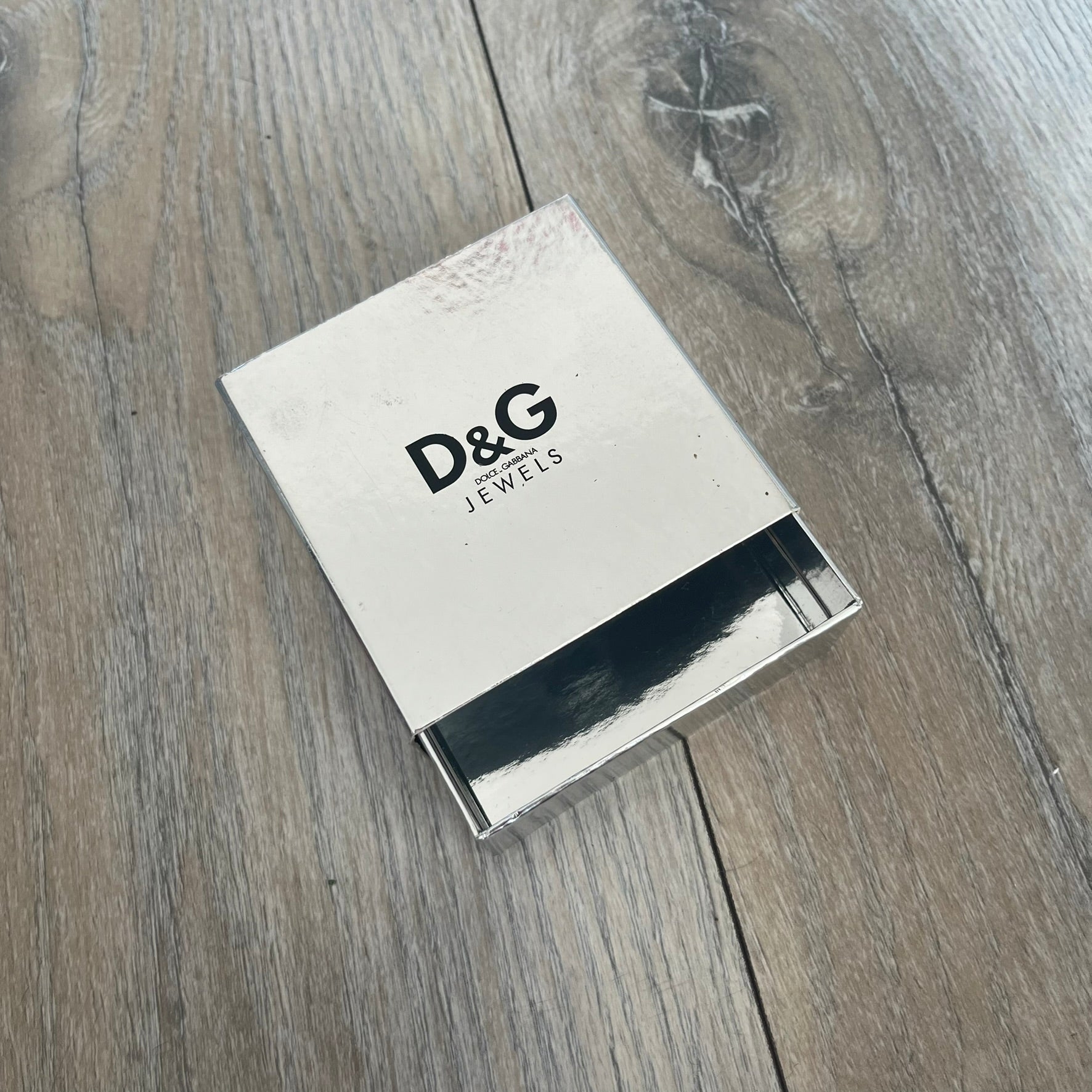 Dolce & Gabbana “D&G IS MY MENTOR” Bracelet is a gold leather bracelet with a glossy finish. The bracelet features line cutout detailing throughout and fastens with two snap-button closures on the back. A gold-tone metal plaque on the front is engraved with “D&G IS MY MENTOR.” The bracelet comes with its original box.
