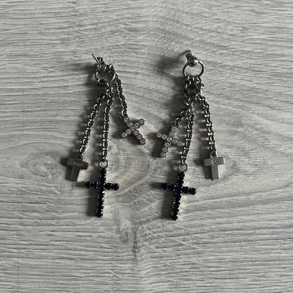 Dolce & Gabbana Dangle Drop Cross Earrings. Pair of earrings featuring three crosses of varying lengths on each, including one with black stones, one with clear stones, and one full metal cross with a D&G logo and a small clear stone. Comes with original box and dustbag