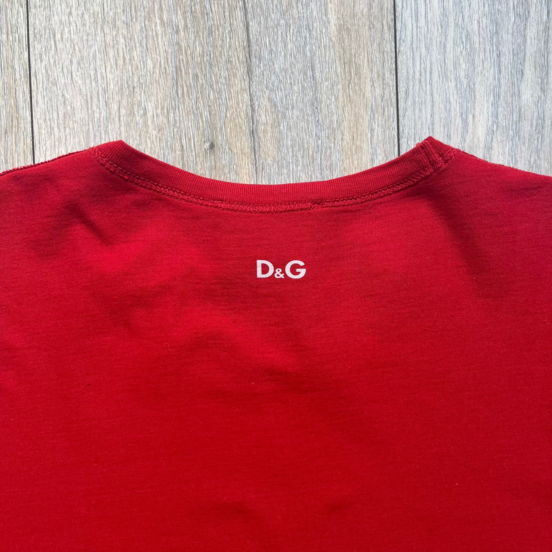 Dolce &amp; Gabbana Fall 2011 tee in vibrant red featuring a simple “Drink Coca-Cola” logo on the chest. Designed with an inside-out stitching aesthetic and a subtle back logo under the collar. A unique, collectible tee that merges casual branding with high-fashion flair.