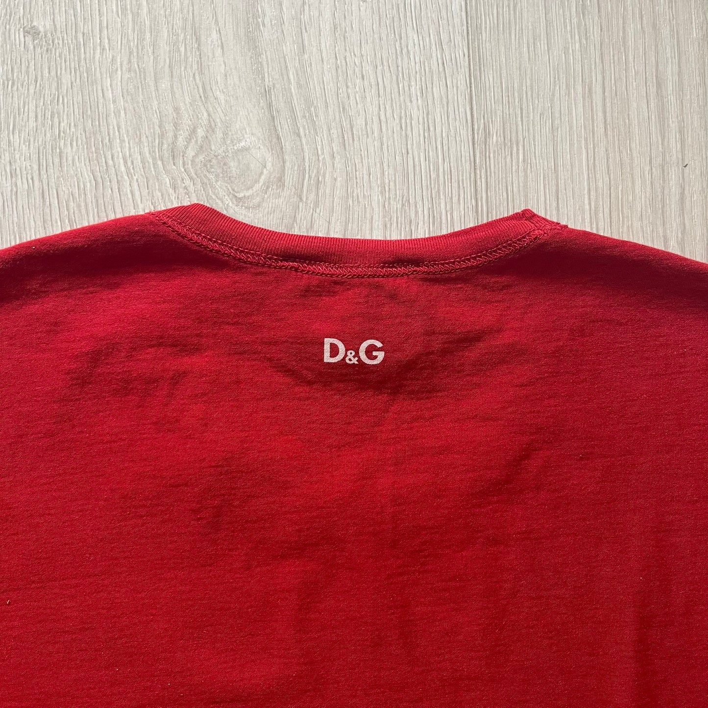 Dolce &amp; Gabbana Fall 2011 tee in vibrant red featuring a simple “Drink Coca-Cola” logo on the chest. Designed with an inside-out stitching aesthetic and a subtle back logo under the collar. A unique, collectible tee that merges casual branding with high-fashion flair.