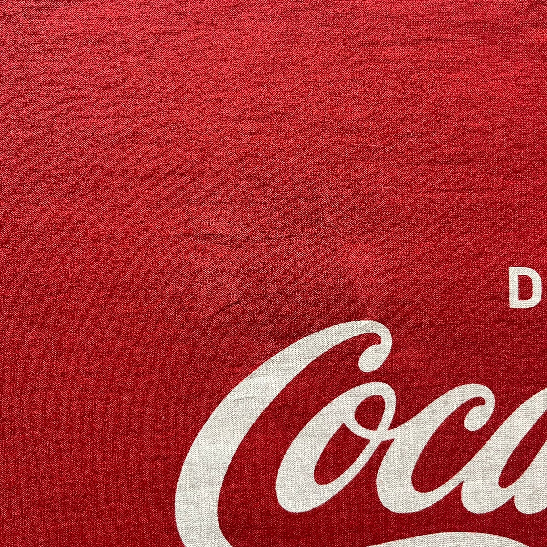 Dolce &amp; Gabbana Fall 2011 tee in vibrant red featuring a simple “Drink Coca-Cola” logo on the chest. Designed with an inside-out stitching aesthetic and a subtle back logo under the collar. A unique, collectible tee that merges casual branding with high-fashion flair.