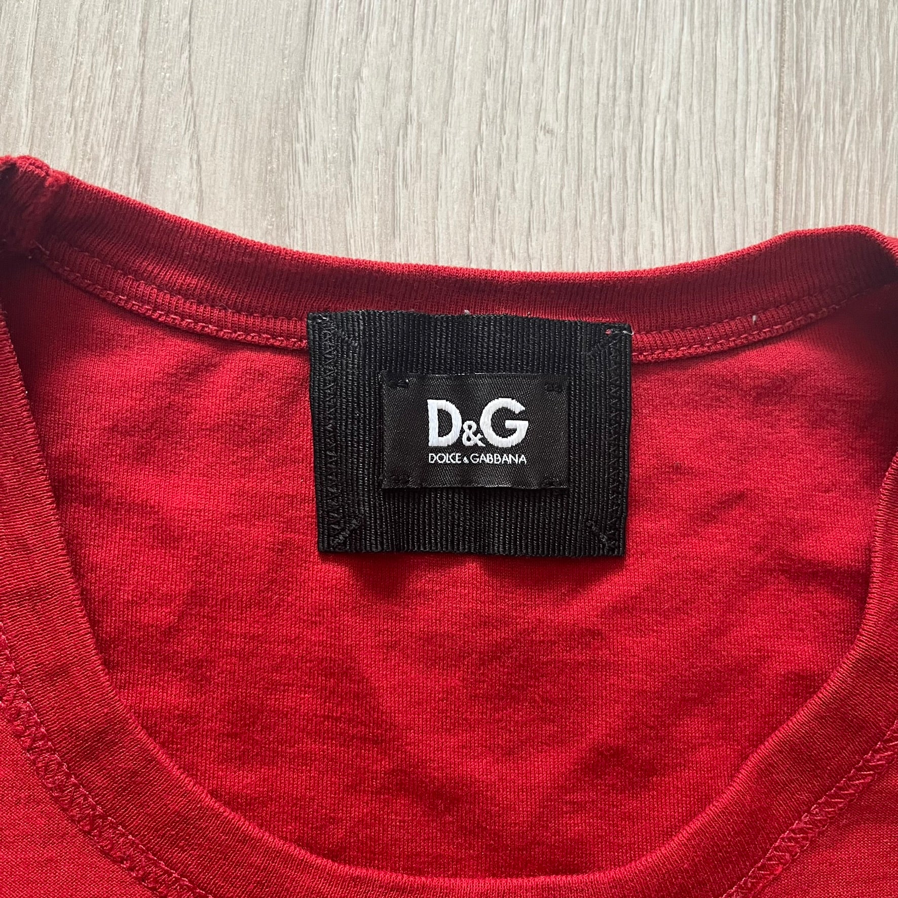 Dolce &amp; Gabbana Fall 2011 tee in vibrant red featuring a simple “Drink Coca-Cola” logo on the chest. Designed with an inside-out stitching aesthetic and a subtle back logo under the collar. A unique, collectible tee that merges casual branding with high-fashion flair.