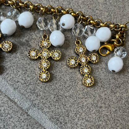 Dolce &amp; Gabbana Gold Charm Cross DJ0250 Bracelet features a gold-tone chain bracelet with white bead charms, six cross-shaped charms made from circular elements, and a D&amp;G logo charm. The bracelet has a gold-tone metal construction.&nbsp;