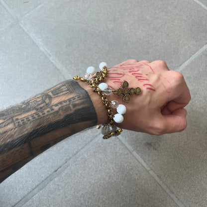 Dolce &amp; Gabbana Gold Charm Cross DJ0250 Bracelet features a gold-tone chain bracelet with white bead charms, six cross-shaped charms made from circular elements, and a D&amp;G logo charm. The bracelet has a gold-tone metal construction.&nbsp;