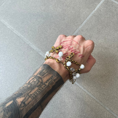 Dolce &amp; Gabbana Gold Charm Cross DJ0250 Bracelet features a gold-tone chain bracelet with white bead charms, six cross-shaped charms made from circular elements, and a D&amp;G logo charm. The bracelet has a gold-tone metal construction.&nbsp;