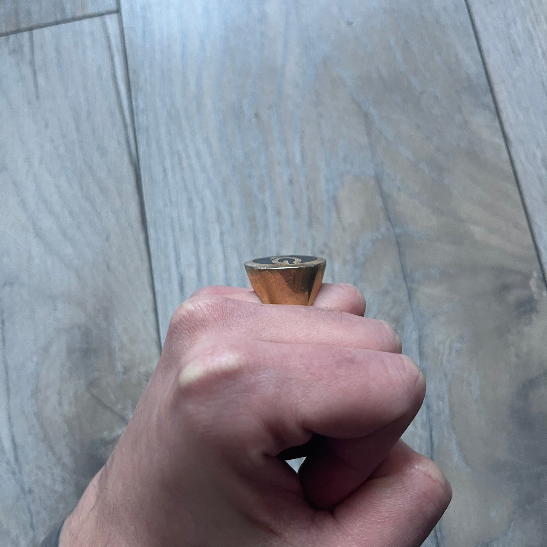 The Dolce & Gabbana Gold Logo Signet Ring is a gold-tone metal signet ring with a thick, substantial design. The top features a black background with the D&G logo in gold tone, outlined in gold. The signet is large and solid.