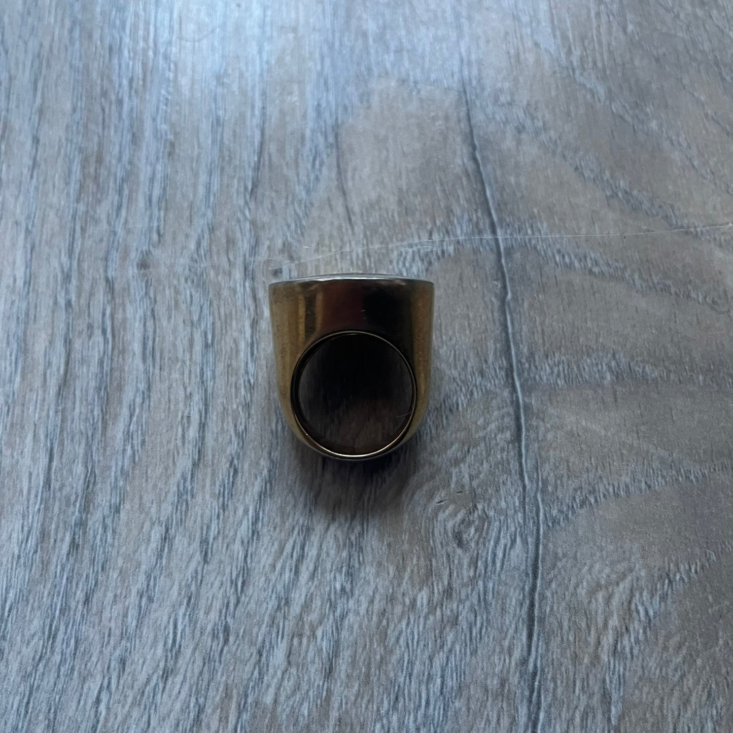 The Dolce & Gabbana Gold Logo Signet Ring is a gold-tone metal signet ring with a thick, substantial design. The top features a black background with the D&G logo in gold tone, outlined in gold. The signet is large and solid.