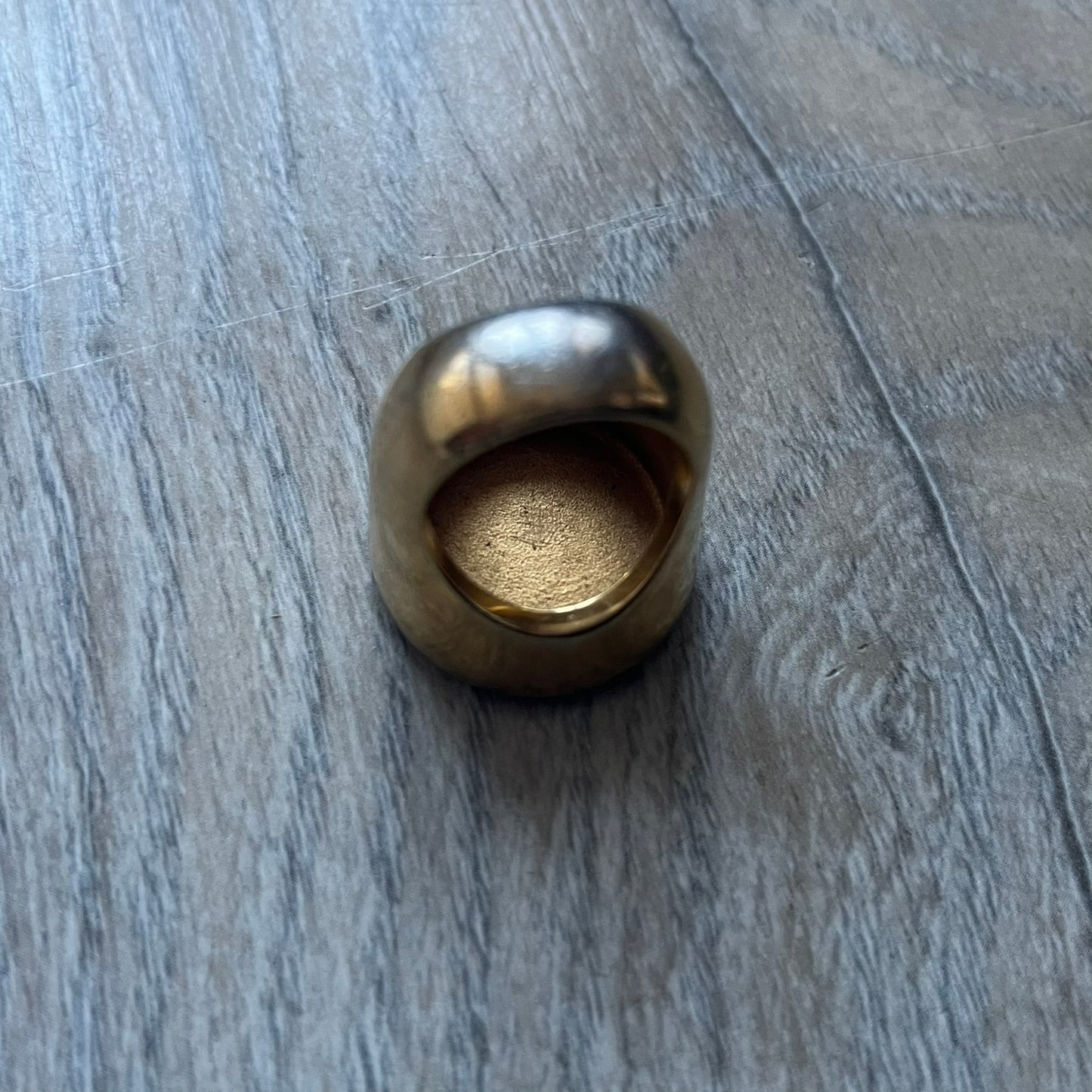 The Dolce & Gabbana Gold Logo Signet Ring is a gold-tone metal signet ring with a thick, substantial design. The top features a black background with the D&G logo in gold tone, outlined in gold. The signet is large and solid.
