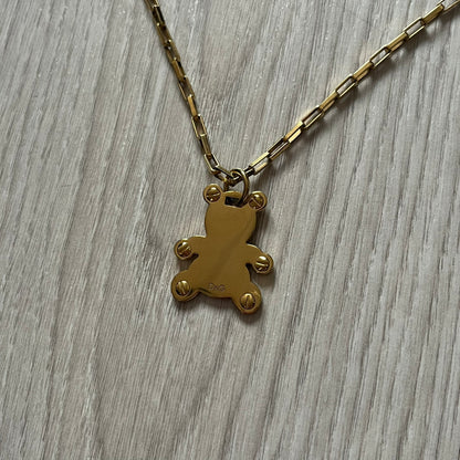The Dolce & Gabbana Teddy Bear Necklace from the 2000s features a flat gold-tone teddy bear pendant detailed with six visible screws and a small D&G logo at the bottom. It hangs from a paperclip chain with a lobster clasp closure, it comes with a silver D&G Jewels bag.