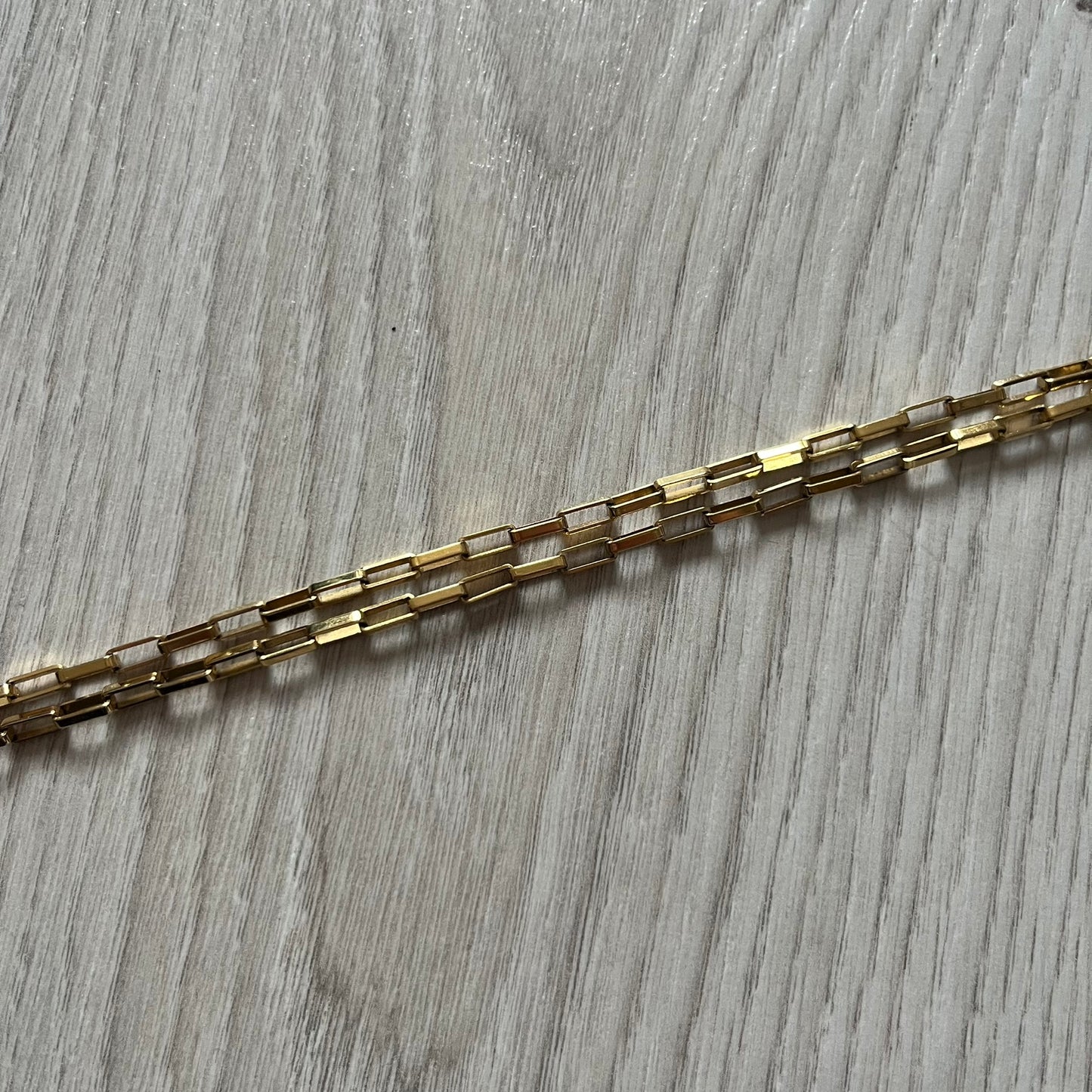 The Dolce & Gabbana Teddy Bear Necklace from the 2000s features a flat gold-tone teddy bear pendant detailed with six visible screws and a small D&G logo at the bottom. It hangs from a paperclip chain with a lobster clasp closure, it comes with a silver D&G Jewels bag.