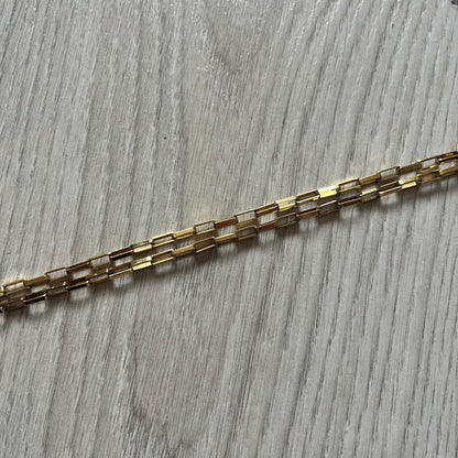 The Dolce & Gabbana Teddy Bear Necklace from the 2000s features a flat gold-tone teddy bear pendant detailed with six visible screws and a small D&G logo at the bottom. It hangs from a paperclip chain with a lobster clasp closure, it comes with a silver D&G Jewels bag.