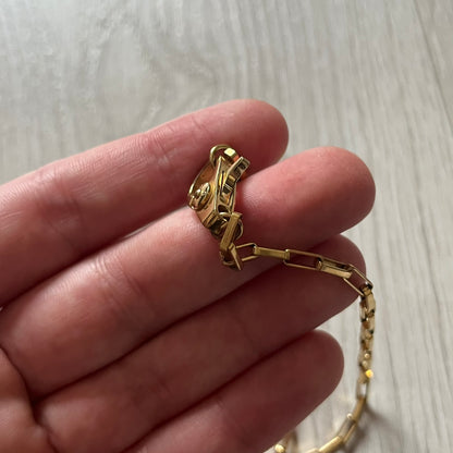 The Dolce & Gabbana Teddy Bear Necklace from the 2000s features a flat gold-tone teddy bear pendant detailed with six visible screws and a small D&G logo at the bottom. It hangs from a paperclip chain with a lobster clasp closure, it comes with a silver D&G Jewels bag.