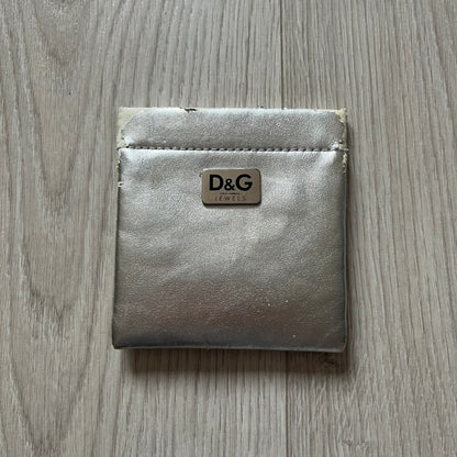 The Dolce & Gabbana Teddy Bear Necklace from the 2000s features a flat gold-tone teddy bear pendant detailed with six visible screws and a small D&G logo at the bottom. It hangs from a paperclip chain with a lobster clasp closure, it comes with a silver D&G Jewels bag.