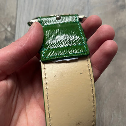 Dolce & Gabbana Green Leather Padlock Buckle Belt features a shiny green leather strap with a beige leather underside. The belt has metal-outlined eyelets for the holes and a clean, simple silver-tone buckle. Next to the buckle is a silver-tone padlock engraved with D&G, along with a fixed metal loop at the center of the belt intended to attach a chain (chain not included).