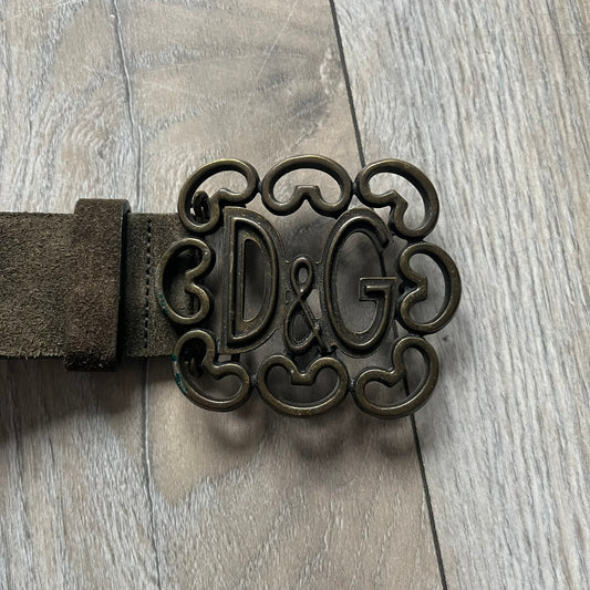 Dolce & Gabbana Green Suede Hearts Belt is made from very dark green suede with an orange leather interior featuring large dot detailing. The buckle is a metal D&G logo surrounded by eight heart shapes pointing outward, all finished in a dark, aged-looking metal tone. The belt comes with the original hologram tag attached.