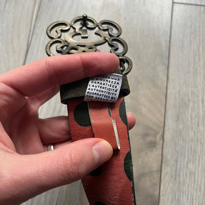 Dolce & Gabbana Green Suede Hearts Belt is made from very dark green suede with an orange leather interior featuring large dot detailing. The buckle is a metal D&G logo surrounded by eight heart shapes pointing outward, all finished in a dark, aged-looking metal tone. The belt comes with the original hologram tag attached.