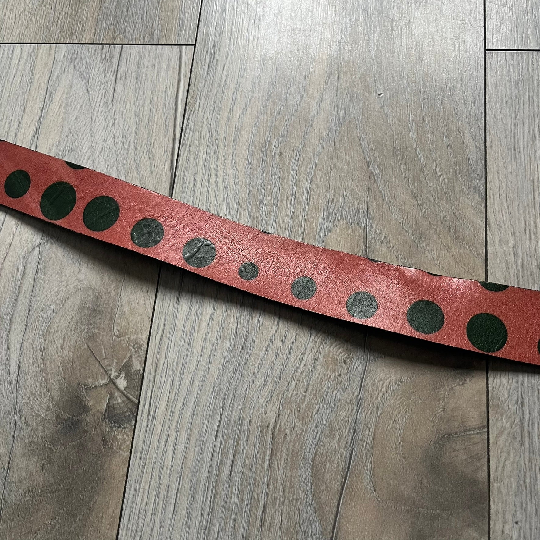 Dolce & Gabbana Green Suede Hearts Belt is made from very dark green suede with an orange leather interior featuring large dot detailing. The buckle is a metal D&G logo surrounded by eight heart shapes pointing outward, all finished in a dark, aged-looking metal tone. The belt comes with the original hologram tag attached.