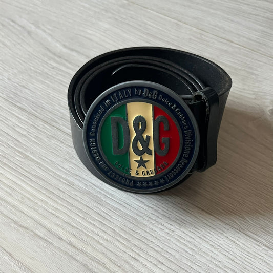 2000's Dolce &amp; Gabbana black leather belt featuring a circular dark silver-tone metal buckle with the Italian flag and D&amp;G logo in the center. The buckle is bordered by a navy ring with engraved text reading “Project And Design Conceived In Italy By Dolce &amp; Gabbana”.