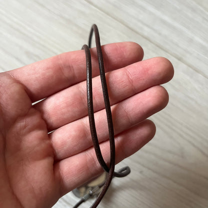 Dolce &amp; Gabbana double dog tag necklace featuring two layered pendants: a italy flag tag underneath and a silver-tone tag on top with a cut-out D&amp;G logo revealing the tricolor tag beneath. Designed with brown leather-ish string.