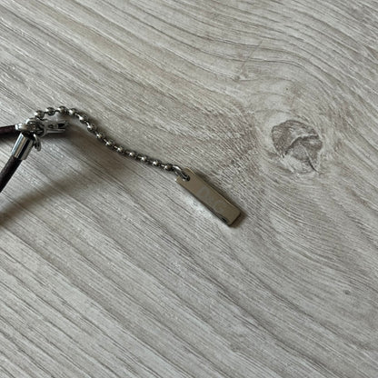 Dolce &amp; Gabbana double dog tag necklace featuring two layered pendants: a italy flag tag underneath and a silver-tone tag on top with a cut-out D&amp;G logo revealing the tricolor tag beneath. Designed with brown leather-ish string.