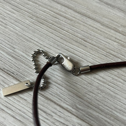 Dolce &amp; Gabbana double dog tag necklace featuring two layered pendants: a italy flag tag underneath and a silver-tone tag on top with a cut-out D&amp;G logo revealing the tricolor tag beneath. Designed with brown leather-ish string.