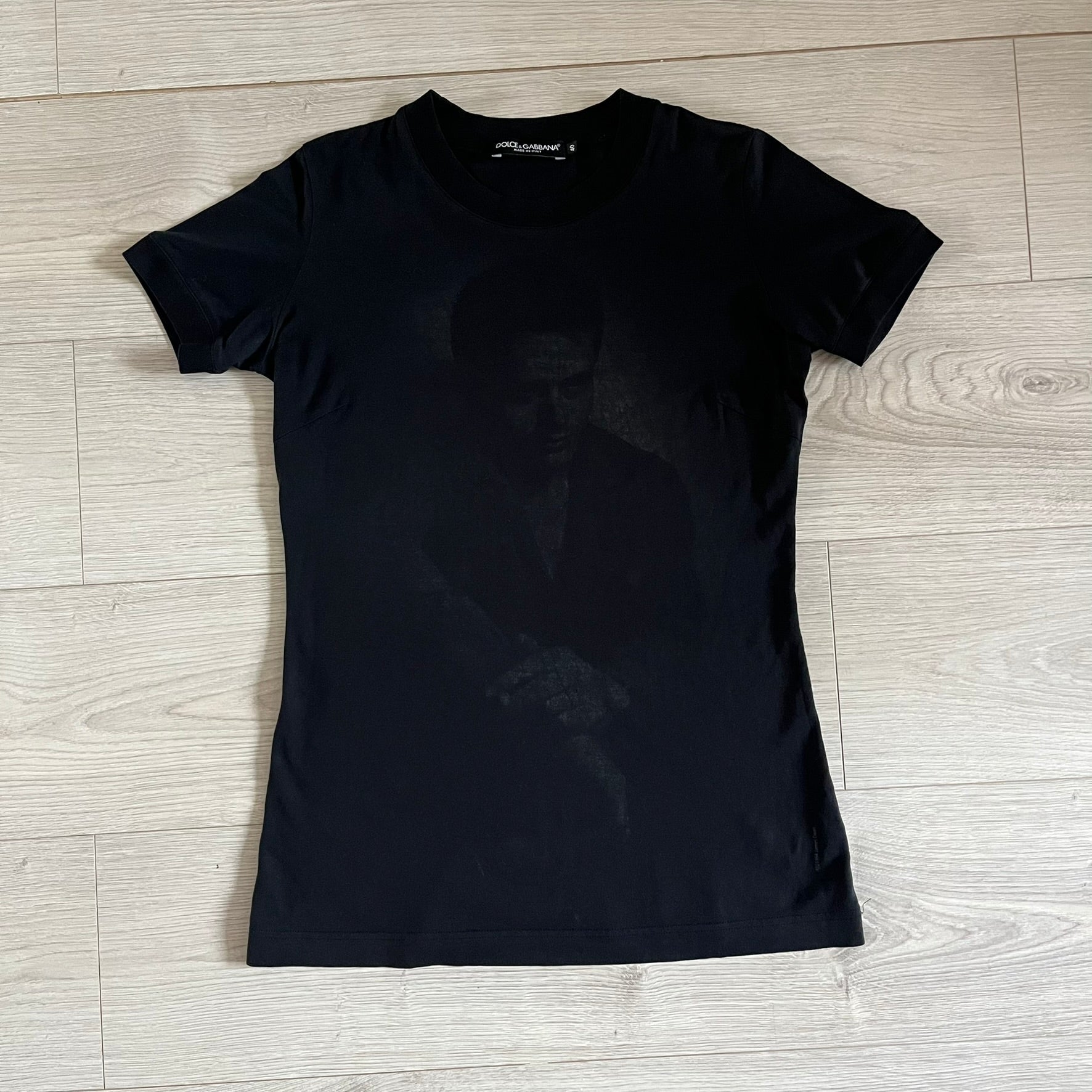 This Dolce &amp; Gabbana James Dean Black Tee features a premium Italian-made cotton construction with a front portrait of James. The design includes pretty big white/grey “James Dean” text across the upper back. The t-shirt celebrates the lasting influence of James Dean, a defining figure of mid-century cinema.