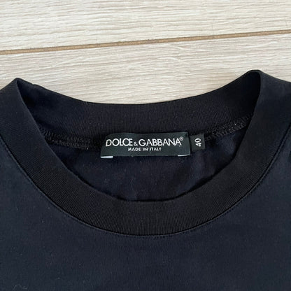 This Dolce &amp; Gabbana James Dean Black Tee features a premium Italian-made cotton construction with a front portrait of James. The design includes pretty big white/grey “James Dean” text across the upper back. The t-shirt celebrates the lasting influence of James Dean, a defining figure of mid-century cinema.