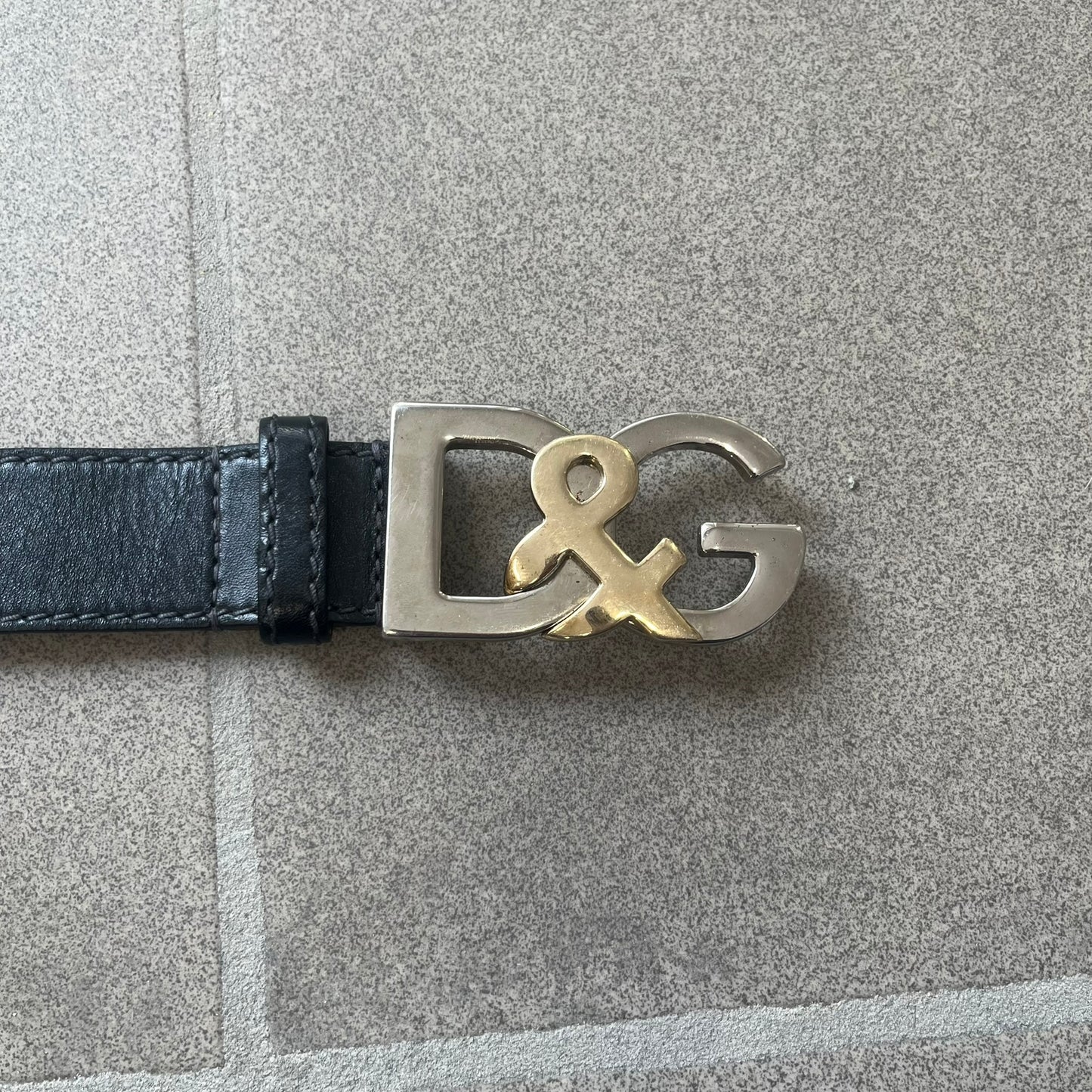 Dolce &amp; Gabbana Kids Logo Black Leather Belt features a black leather strap with a cutout DG logo buckle. The buckle combines a silver-tone “DG” design with a gold-tone ampersand detail. Made in Italy, the belt is crafted from 100% leather.