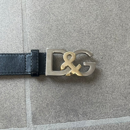 Dolce &amp; Gabbana Kids Logo Black Leather Belt features a black leather strap with a cutout DG logo buckle. The buckle combines a silver-tone “DG” design with a gold-tone ampersand detail. Made in Italy, the belt is crafted from 100% leather.