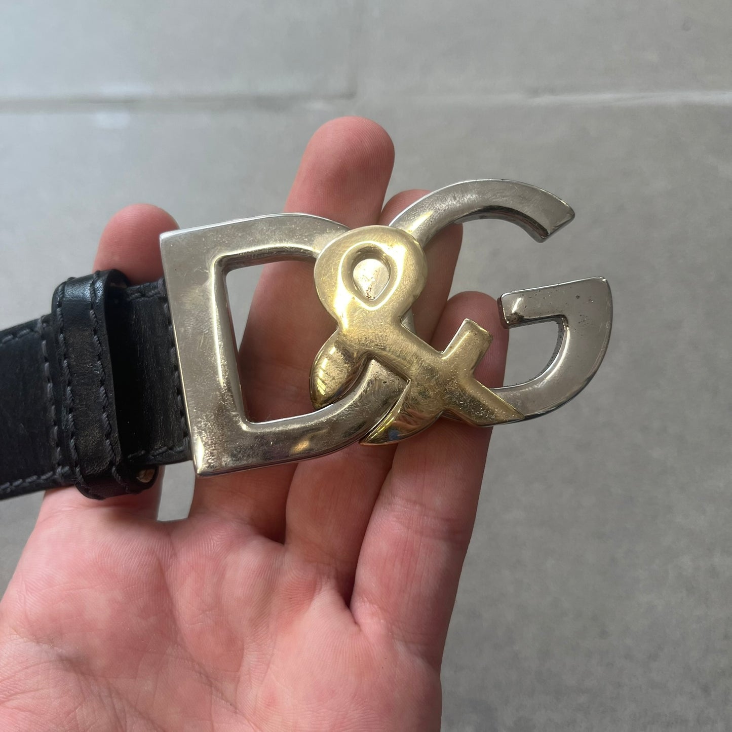 Dolce &amp; Gabbana Kids Logo Black Leather Belt features a black leather strap with a cutout DG logo buckle. The buckle combines a silver-tone “DG” design with a gold-tone ampersand detail. Made in Italy, the belt is crafted from 100% leather.