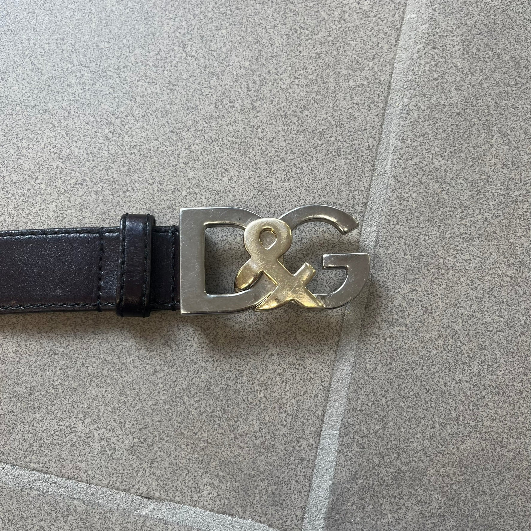 Dolce & Gabbana Kids Logo Brown Leather Belt features a brown leather strap with a cutout D&G logo buckle. The buckle combines a silver-tone “DG” design with a gold-tone ampersand detail. Made in Italy, the belt is crafted from 100% leather.
