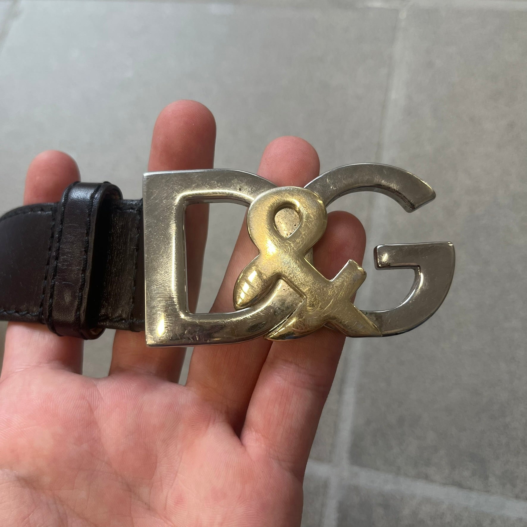 Dolce & Gabbana Kids Logo Brown Leather Belt features a brown leather strap with a cutout D&G logo buckle. The buckle combines a silver-tone “DG” design with a gold-tone ampersand detail. Made in Italy, the belt is crafted from 100% leather.
