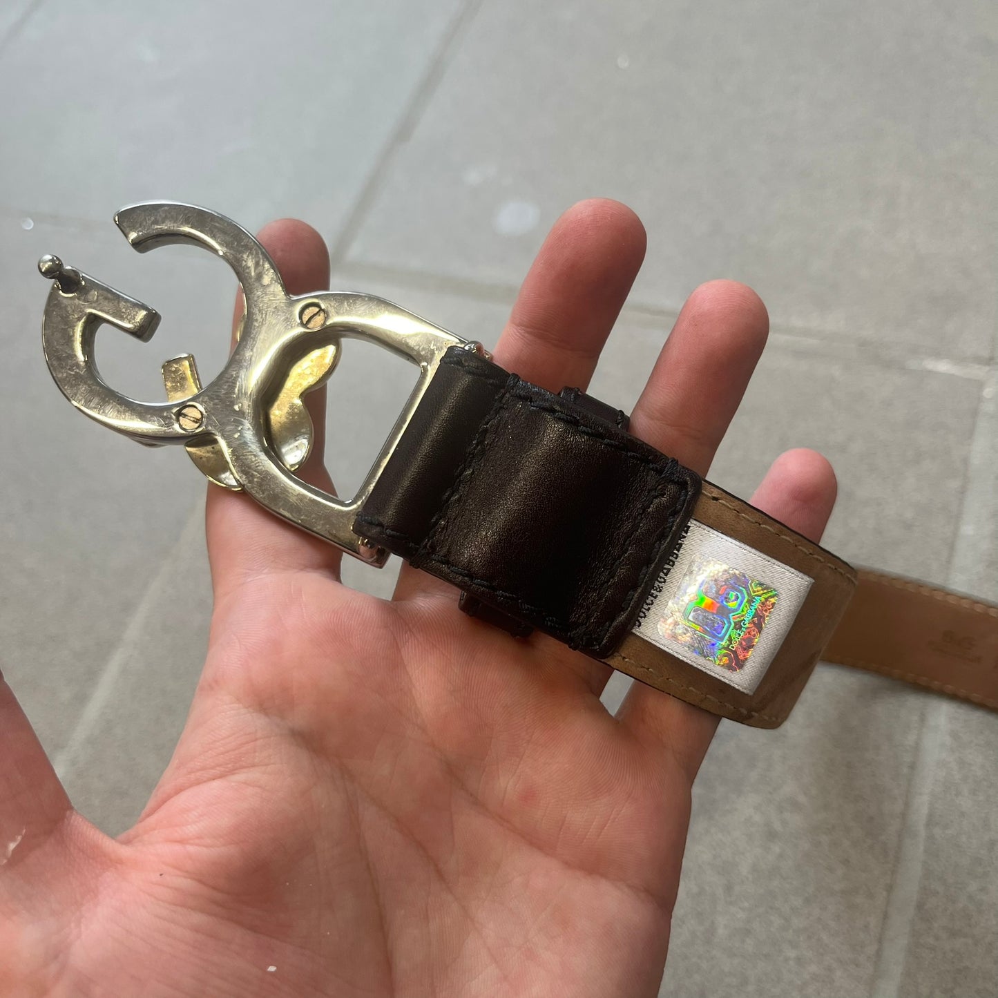 Dolce & Gabbana Kids Logo Brown Leather Belt features a brown leather strap with a cutout D&G logo buckle. The buckle combines a silver-tone “DG” design with a gold-tone ampersand detail. Made in Italy, the belt is crafted from 100% leather.
