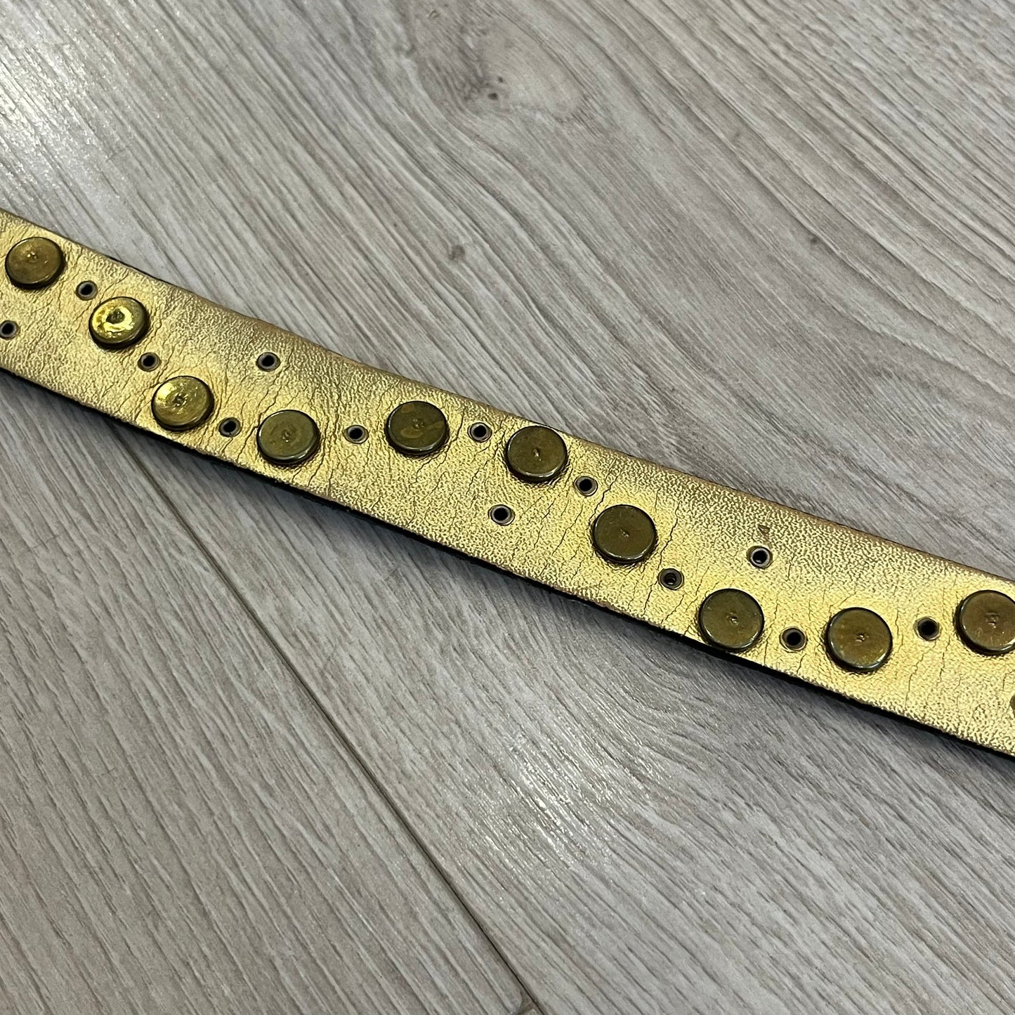 Dolce &amp; Gabbana Leather Studded Belt in black textured leather with a scaled, snake-like finish. The belt features gold stud detailing arranged in a clean pattern and a matching black D&amp;G buckle trimmed with gold hardware and exposed screws. The interior is finished in gold, adding a refined contrast to the overall design.