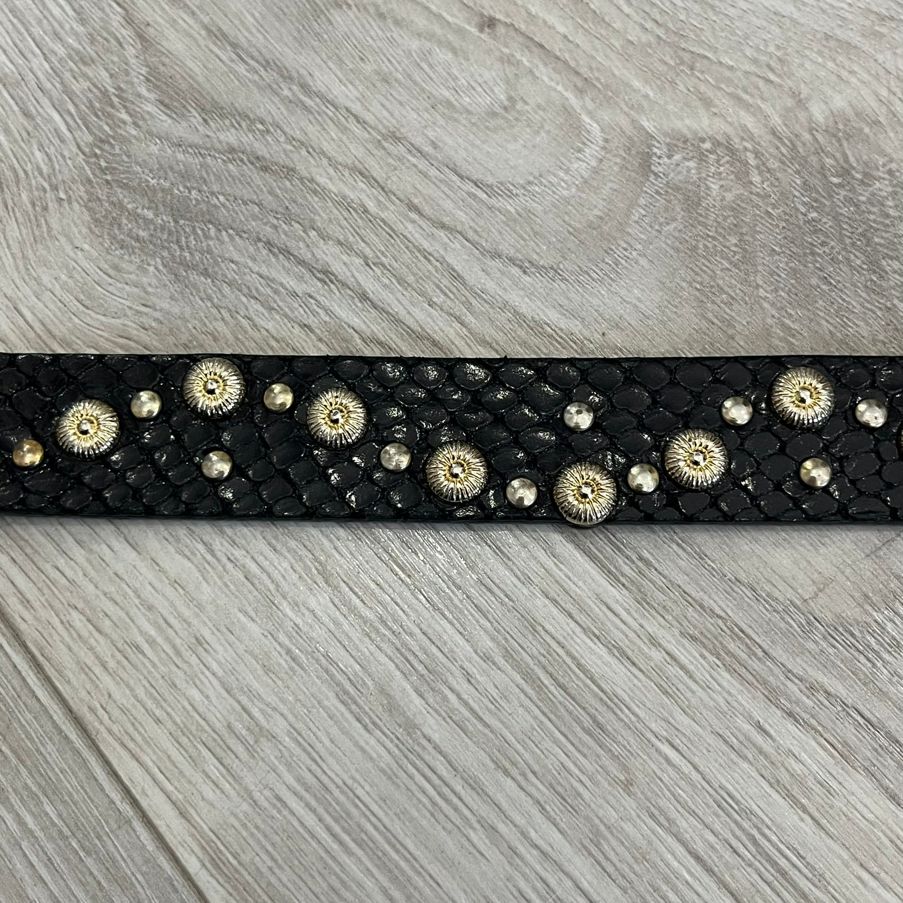 Dolce &amp; Gabbana Leather Studded Belt in black textured leather with a scaled, snake-like finish. The belt features gold stud detailing arranged in a clean pattern and a matching black D&amp;G buckle trimmed with gold hardware and exposed screws. The interior is finished in gold, adding a refined contrast to the overall design.
