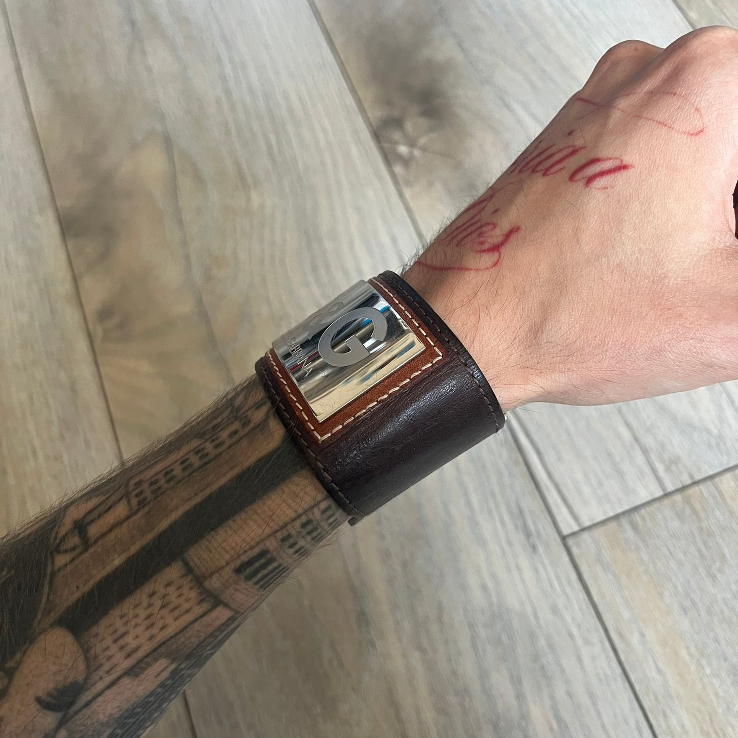 Dolce & Gabbana Logo Leather Bracelet is a leather bracelet made in Italy. It features an adjustable closure and a large stainless steel plaque on the front. The plaque is engraved with the D&G logo and Dolce & Gabbana text. Silver-tone hardware is used throughout the bracelet.