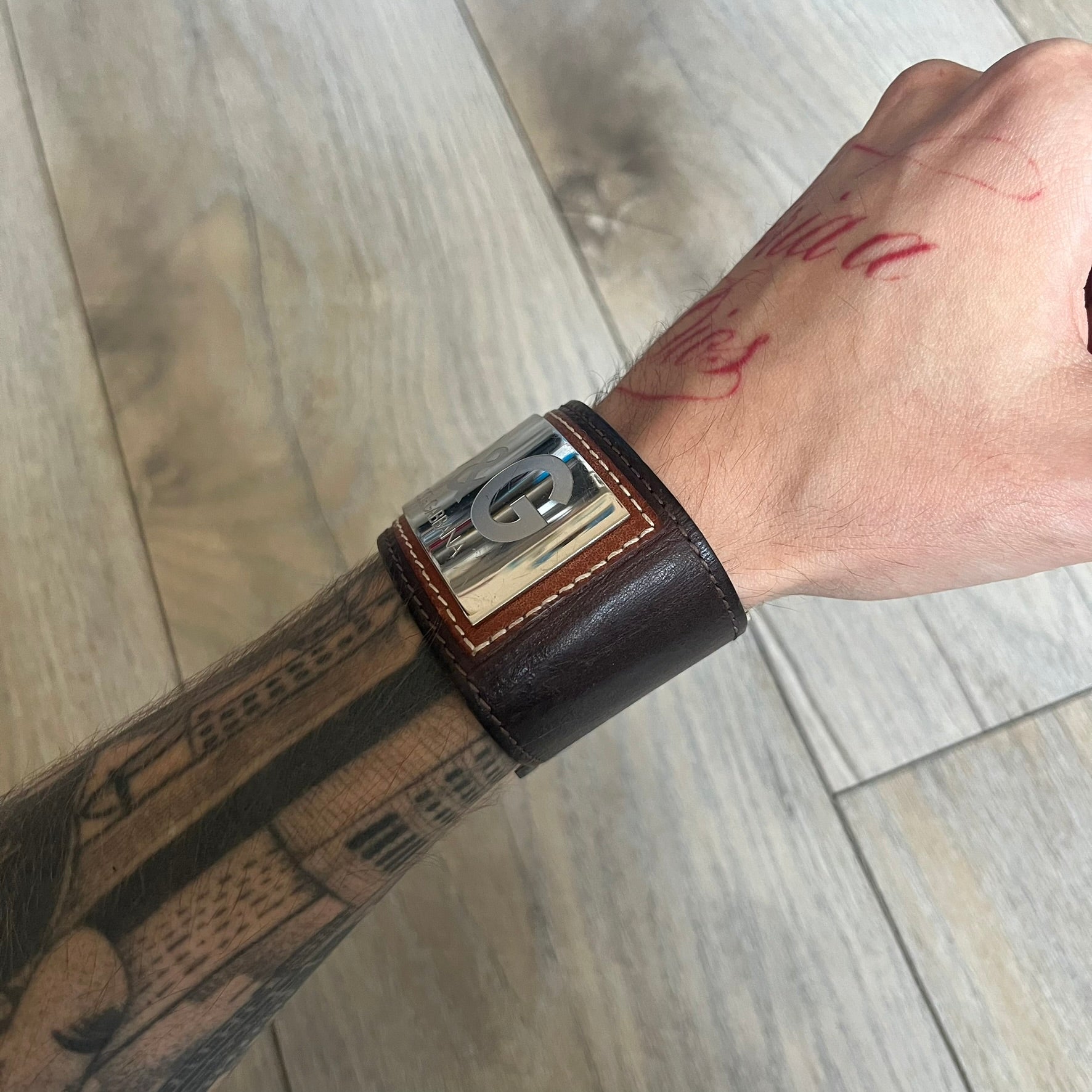 Dolce & Gabbana Logo Leather Bracelet is a leather bracelet made in Italy. It features an adjustable closure and a large stainless steel plaque on the front. The plaque is engraved with the D&G logo and Dolce & Gabbana text. Silver-tone hardware is used throughout the bracelet.