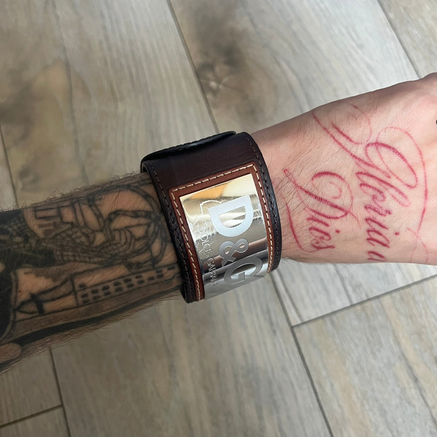Dolce & Gabbana Logo Leather Bracelet is a leather bracelet made in Italy. It features an adjustable closure and a large stainless steel plaque on the front. The plaque is engraved with the D&G logo and Dolce & Gabbana text. Silver-tone hardware is used throughout the bracelet.