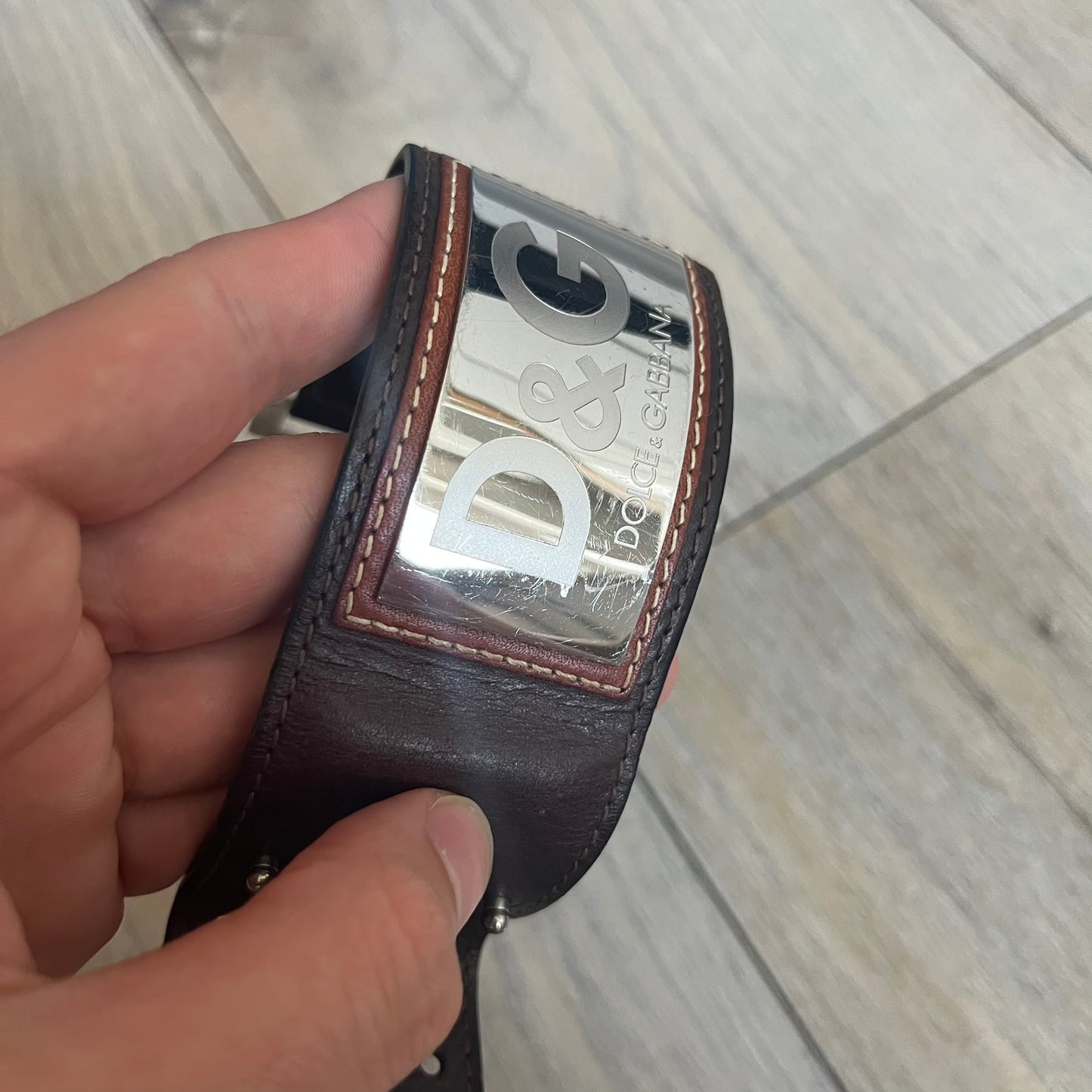 Dolce & Gabbana Logo Leather Bracelet is a leather bracelet made in Italy. It features an adjustable closure and a large stainless steel plaque on the front. The plaque is engraved with the D&G logo and Dolce & Gabbana text. Silver-tone hardware is used throughout the bracelet.