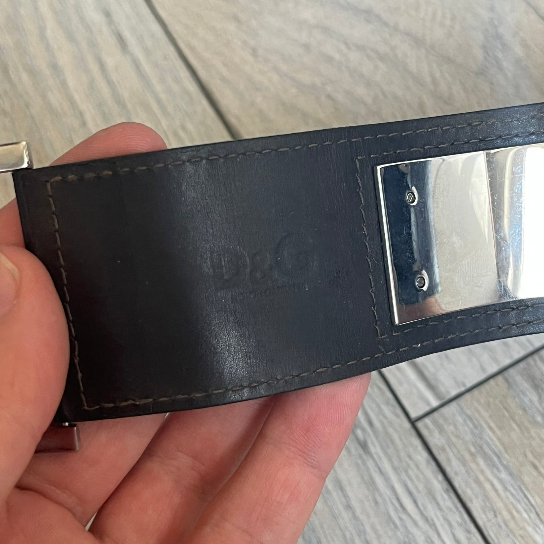 Dolce & Gabbana Logo Leather Bracelet is a leather bracelet made in Italy. It features an adjustable closure and a large stainless steel plaque on the front. The plaque is engraved with the D&G logo and Dolce & Gabbana text. Silver-tone hardware is used throughout the bracelet.