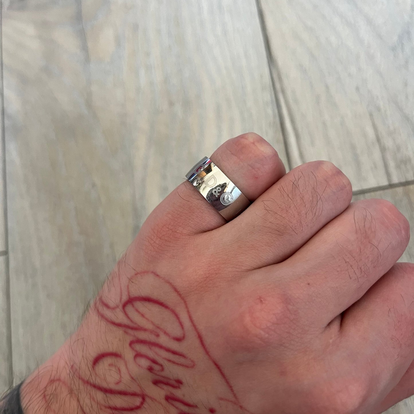 Dolce & Gabbana Logo Repeat Ring is a stainless steel ring featuring repeating engraved D&G logos around the entire band. The design is minimal and clean, focusing on subtle branded detailing and polished metal construction.