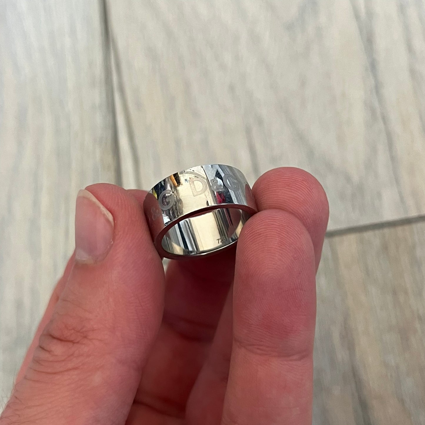 Dolce & Gabbana Logo Repeat Ring is a stainless steel ring featuring repeating engraved D&G logos around the entire band. The design is minimal and clean, focusing on subtle branded detailing and polished metal construction.