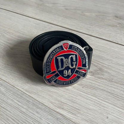 Dolce &amp; Gabbana "Made with Pride" Belt crafted from smooth black Italian leather. Features a circular silver buckle with D&amp;G 94 at the center, surrounded by “Proud to Wear D&amp;G,” “Made with Pride,” and “Established 1994” text. Finished with subtle red and navy accents, combining classic craftsmanship with contemporary flair.